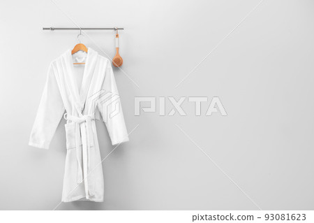 Hanger with clean bathrobe and brush on light wall. Space for text 93081623