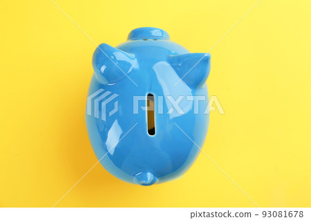 Blue piggy bank on yellow background, top view Blue piggy bank on yellow background, top view 93081678