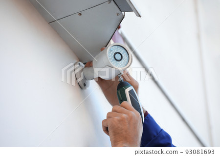 Technician installing CCTV camera on wall outdoors, closeup Technician installing CCTV camera on wall outdoors, closeup 93081693