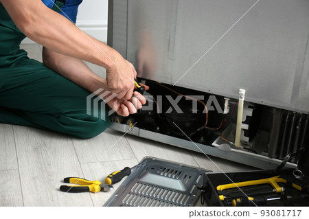 Male technician with pliers repairing refrigerator indoors, closeup Male technician with pliers repairing refrigerator indoors, closeup 93081717