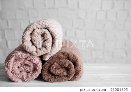 Fresh rolled bath towels on white wooden table. Space for text 93081895