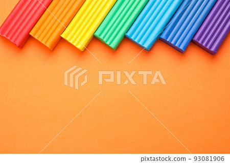 Colorful bars of modeling clay on orange background, flat lay with space for text. Rainbow palette Colorful bars of modeling clay on orange background, flat lay with space for text. Rainbow palette 93081906