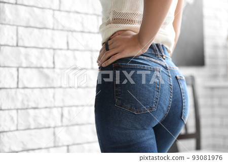 Woman wearing jeans near brick wall indoors, closeup Woman wearing jeans near brick wall indoors, closeup 93081976