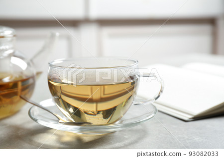 Tasty hot green tea in cup on grey table, closeup Tasty hot green tea in cup on grey table, closeup 93082033