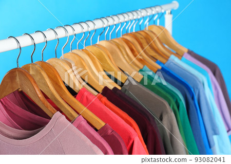 Colorful clothes on hangers against light blue background 93082041