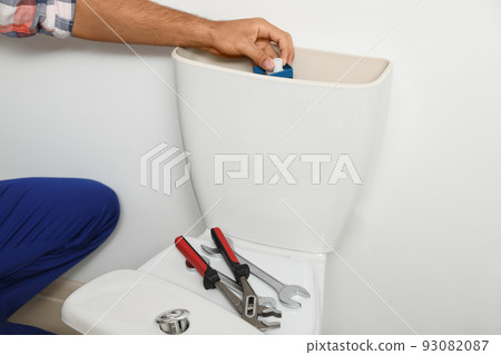 Professional plumber working with toilet bowl in bathroom, closeup 93082087