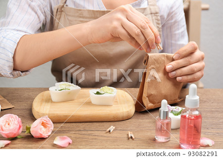 Woman holding paper bag with natural handmade soap at wooden table, closeup 93082291
