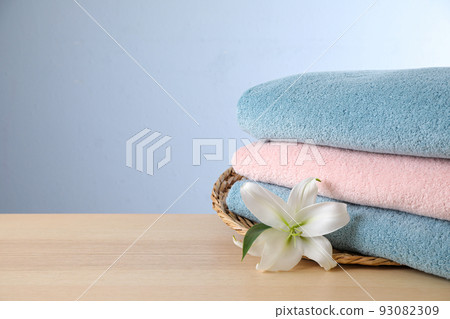 Stack of clean bath towels and beautiful flower on wooden table. Space for text 93082309