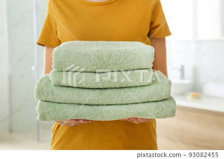 Woman holding fresh towels in bathroom, closeup Woman holding fresh towels in bathroom, closeup 93082455