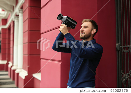 Young man with vintage video camera outdoors 93082576