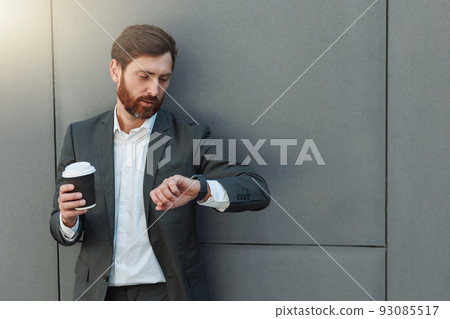 Focused european businessman in suit with coffee watching on his wrist watch during break 93085517