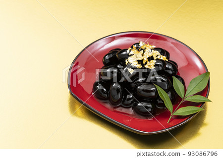 New Year dishes 2 _ black beans with gold leaf on a red plate _ background gold 93086796