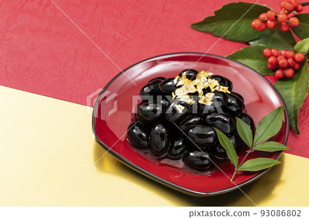 New Year dishes 2 _ black beans with gold leaf on a red plate _ background red, gold and Nanten 93086802