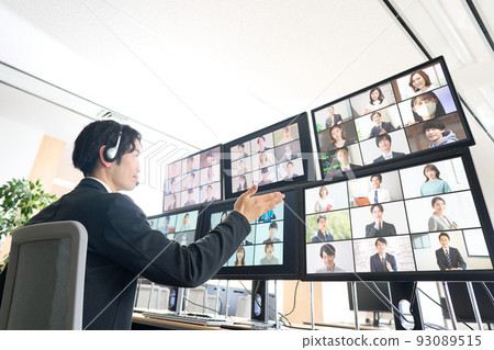 一名男子一邊看多台顯示器,一邊與很多人進行視頻會議 一名男子一邊看多台顯示器,一邊與很多人進行視頻會議 93089515