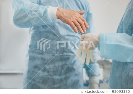 Close up of surgeon hands puts on gloves in the operating room preparing for surgery Close up of surgeon hands puts on gloves in the operating room preparing for surgery 93093380