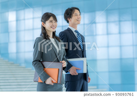 Young businessman and businesswoman standing in office lobby 93093761
