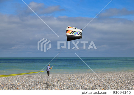 A man controls a kite on the shores of the Atlantic Ocean A man controls a kite on the shores of the Atlantic Ocean 93094340