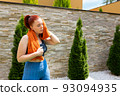 Attractive young sportswoman drying her sweat with a towel after exercising outdoors in the garden of her home. concept of health and well-being. 93094935