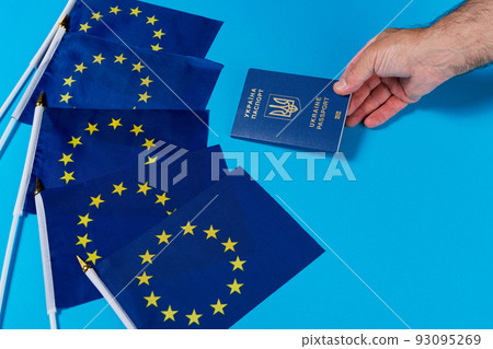 five flags of the eu and a hand holding out a passport of ukraine, the concept of joining the european union five flags of the eu and a hand holding out a passport of ukraine, the concept of joining the european union 93095269