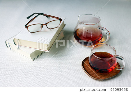 讀書、眼鏡、茶倒進玻璃杯和白色背景的茶壺之間的茶時間 93095668