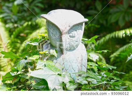 Owl statue standing in the green nature Owl statue standing in the green nature 93096012
