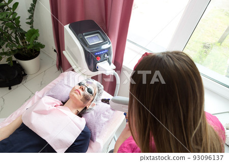Spa salon client woman on carbon laser peeling procedure Spa salon client woman on carbon laser peeling procedure 93096137