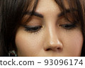 Glamour close-up portrait of beautiful woman model face with winged black eyeliner make-up, clean skin on white background. Long eyelashes and thick eyebrows. 93096174