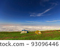 Glowing tents in the mountains under clear sky. Blue sky and mist in the background. Summer landscape. 93096446