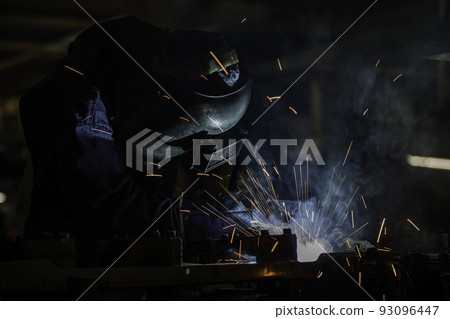 Industrial worker is welding automotive part in factory 93096447