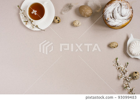 Easter cake, eggs, a cup of tea, sweets, branches of a flowering apple tree and feathers on a beige background. Copy space, flat lay Easter cake, eggs, a cup of tea, sweets, branches of a flowering apple tree and feathers on a beige background. Copy space, flat lay 93099483