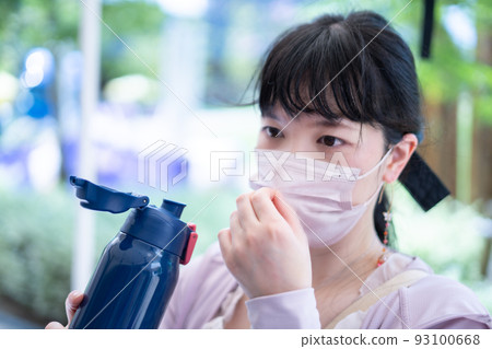 A woman who removes the mask and hydrates with a water bottle 93100668