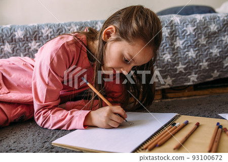 The girl after school plays at home, draws with pencils and felt-tip pens 93100672