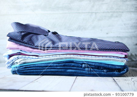 stack of men's shirts and jeans on table  93100779