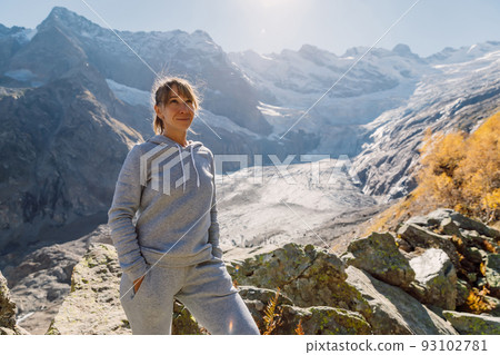 Portrait of smiling lady in the mountains. Mountain with glacier and tourist 93102781