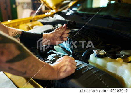 Hands of young man holding detail of car engine over open hood Hands of young man holding detail of car engine over open hood 93103642
