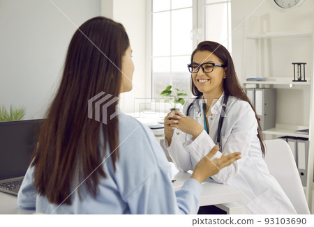 Friendly female doctor listening to her female patient at consultation meeting in hospital office. 93103690