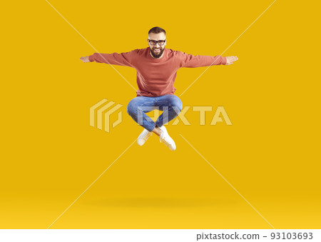Excited energetic young Caucasian man jumping celebrating success posing in orange studio 93103693