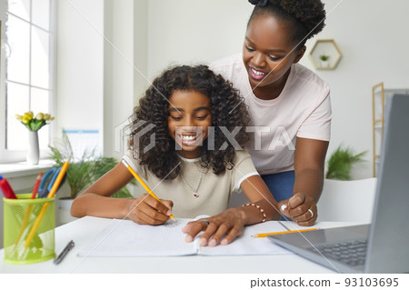 Joyful african american teenage girl doing school homework at home with mom's help. 93103695