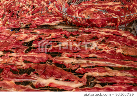 Dried meat slices on a steel grill Dried meat slices on a steel grill 93103759