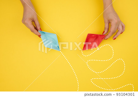 A woman's hand holds paper boats with different trajectories. 93104301