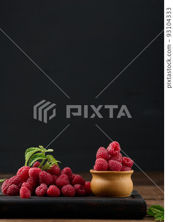Ripe red raspberries on a brown wooden board Ripe red raspberries on a brown wooden board 93104333
