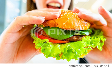 Hamburger vegan healthy vegetarian burger. Salad, avocado, vegetable on veggie sandwich eating cute woman. Tasty vegetarian healthy green food. 93104861