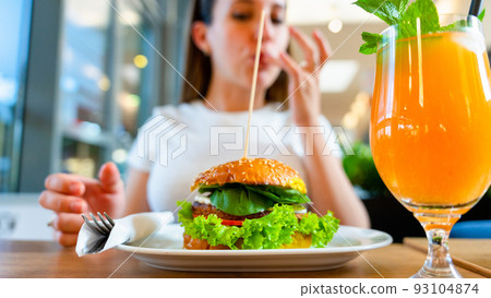 Veggie burger healthy vegan food. Salad, avocado, vegetable on vegetarian hamburger eating cute woman. Vegan sandwich healthy diet food. 93104874