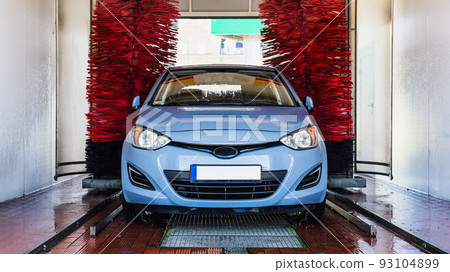 Car washing machine. Auto brush washer clean blue car on automatic carwash station. Automated car washing machine background. Car washing machine. Auto brush washer clean blue car on automatic carwash station. Automated car washing machine background. 93104899