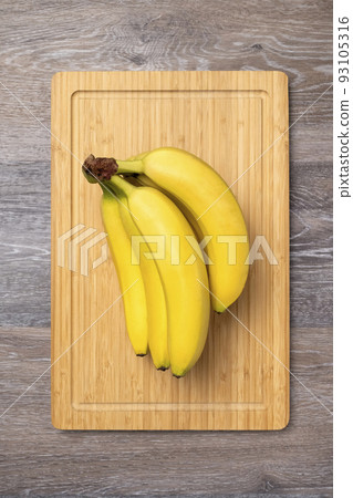 Branch of ripe bananas on a kitchen board Branch of ripe bananas on a kitchen board 93105316