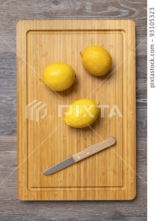 Three ripe lemons on a kitchen board Three ripe lemons on a kitchen board 93105323