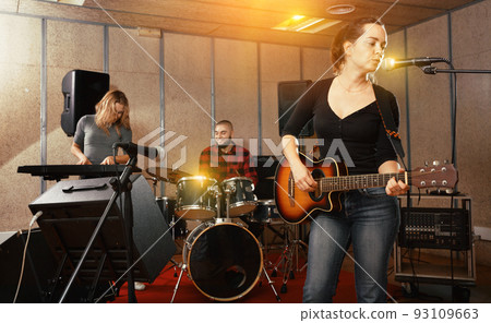 Attractive female soloist playing guitar and singing with her mu Attractive female soloist playing guitar and singing with her mu 93109663