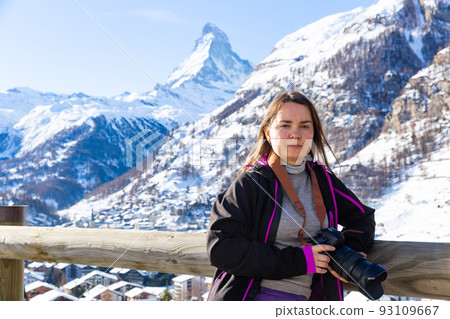 Female traveler with camera enjoying hiking in Swiss Alps in winter Female traveler with camera enjoying hiking in Swiss Alps in winter 93109667