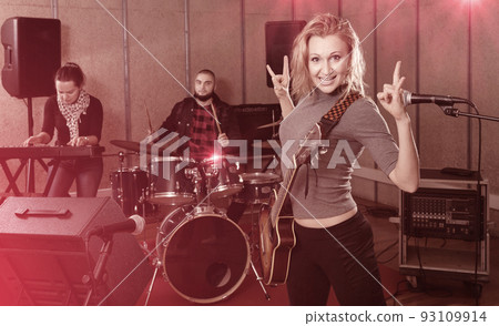 Attractive female soloist playing guitar and singing with her mu Attractive female soloist playing guitar and singing with her mu 93109914