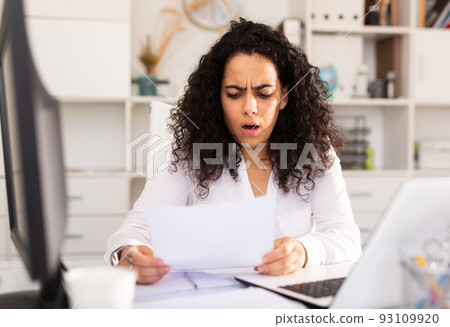 Portrait of worried young female manager working on laptop 93109920